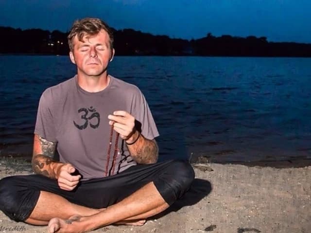 kevin corey meditating with mala beads by the water at dusk in manahawkin, nj